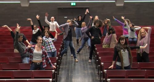 Screenshot des Musikvideos, Studierende tanzen im Hörsaal zum Lied "Happy"