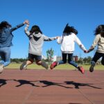 Kinder springen hoch und geben sich die Hände