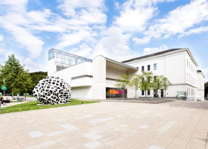 das Hauptgebäude mit einem Kunstwerk davor