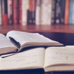Buch, Kugelschreiber und Notizbuch auf TIsch
