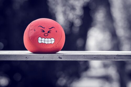 Ein roter Stressball mit aufgedrucktem Smiley, das Anstrengung zeigt