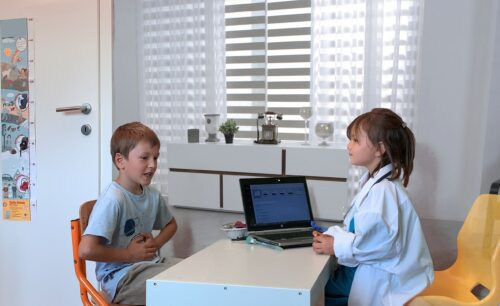 Zwei Kinder sitzen an einem Tisch im Krankenhaus