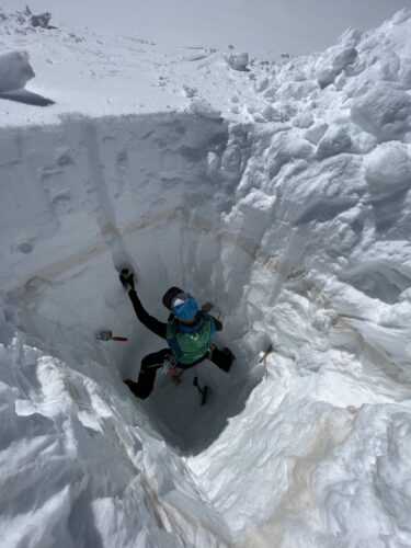 Forscher gräbt sich in die Eisdecke eines Gletschers und steigt hinunter