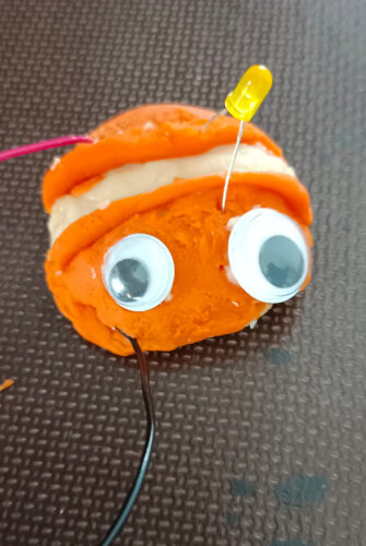 eine Figur aus leitender und nichtleitender Knete mit Kabeln und Leuchtdiode