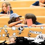 mehrere Kinder, die auf den Bänken in einem Hörsaal sitzen