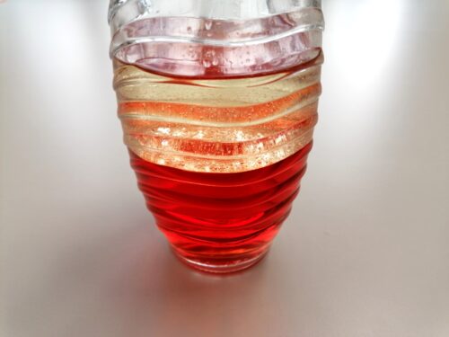 Plastikflasche, gefüllt mit rot gefärbtem Wasser und Pflanzenöl