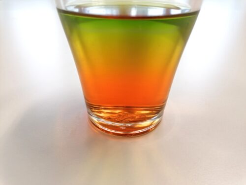 Glas mit unterschiedlich gefärbten Zuckerlösungen