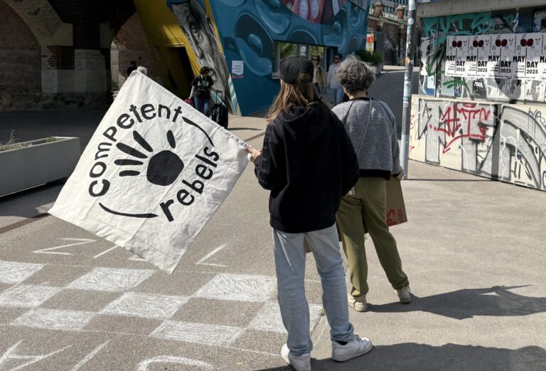 Zwei junge Menschen stehen mit der Flagge der Competent Rebels am Donaukanal und warten