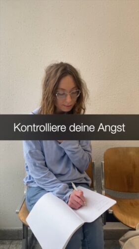 Junge Frau, die über einem Heft sitzt und darüber der Schriftzug "Kontrolliere deine Angst!"
