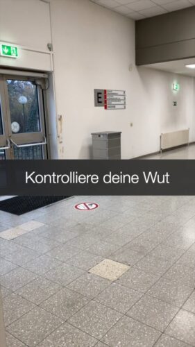 Foyer einer Schule oder Universität und Schriftzug "Kontrolliere deine Wut!"