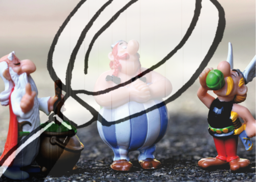 Figuren von Asterix, Obelix und Miraculix mit durchsichtigem Schleier hinter einer großen Lupe